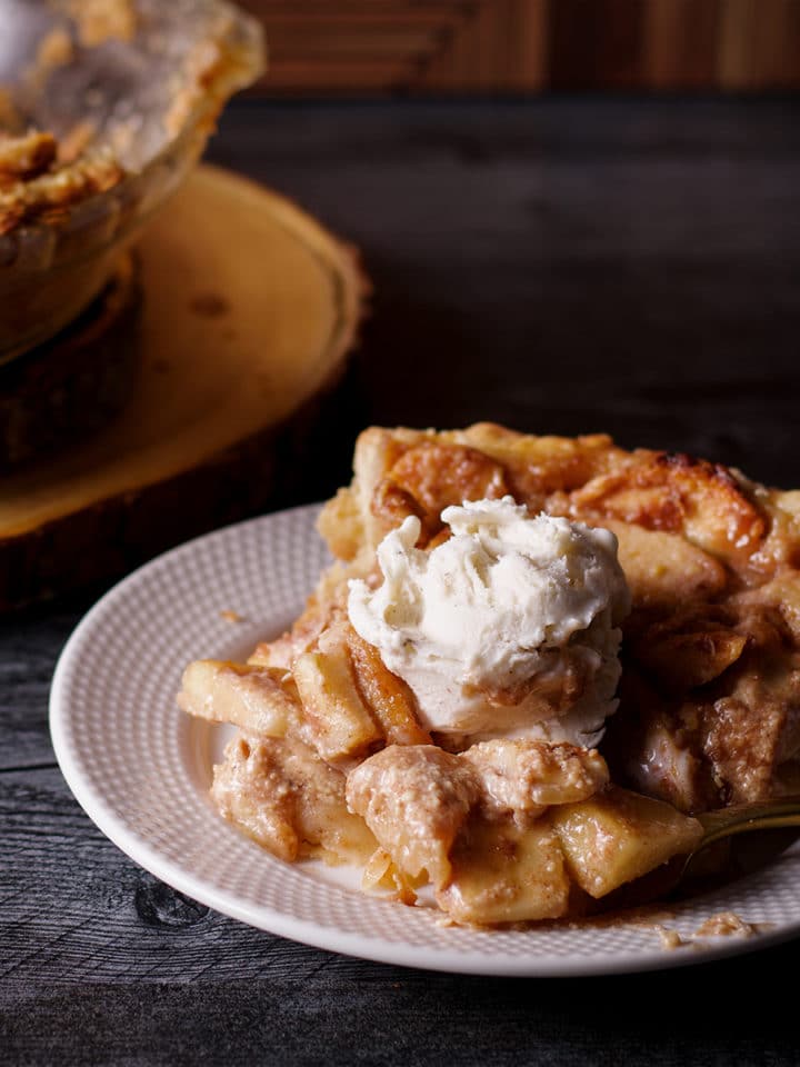 A slice of German Apple Pie topped with a scoop of vanilla ice cream.
