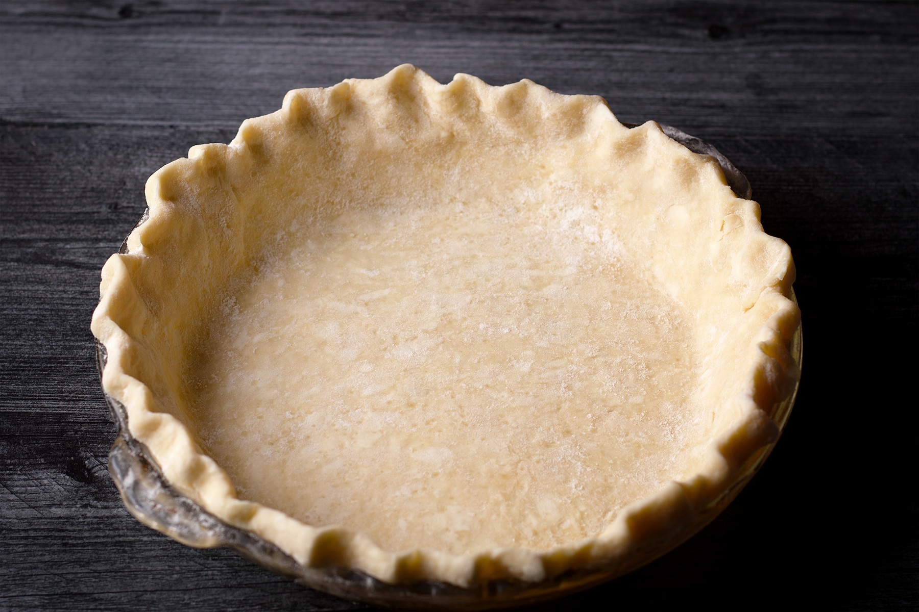 A pie plate that's been fitted with a bottom pie crust.