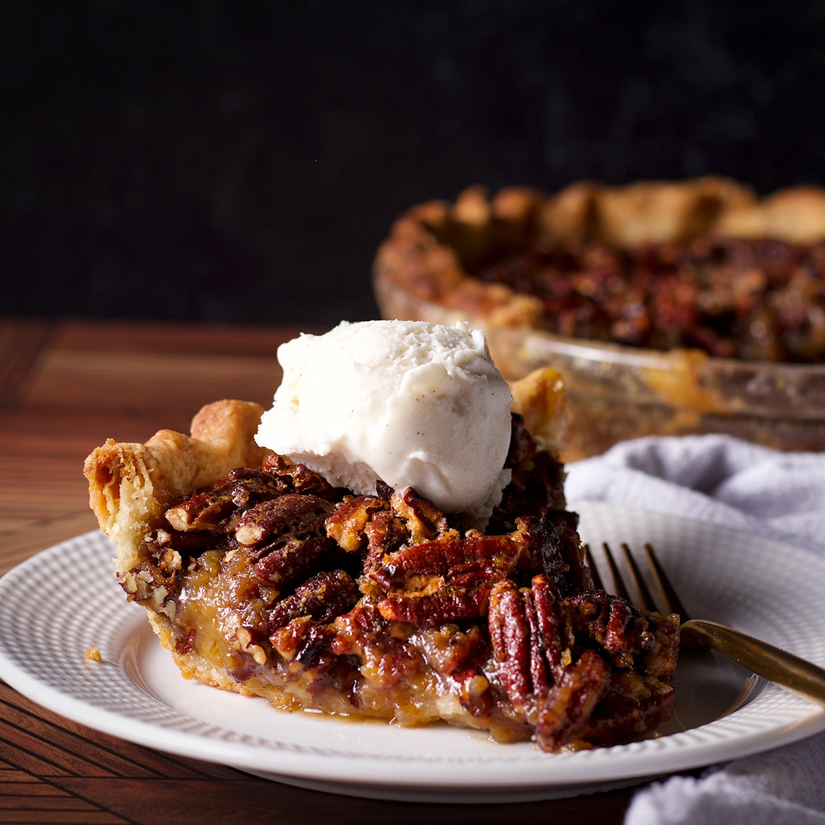 A slice of pecan pie topped with a scoop of vanilla ice cream.