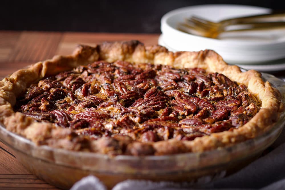 A freshly baked pecan pie, made without corn syrup, on a wood table, ready to serve. 
