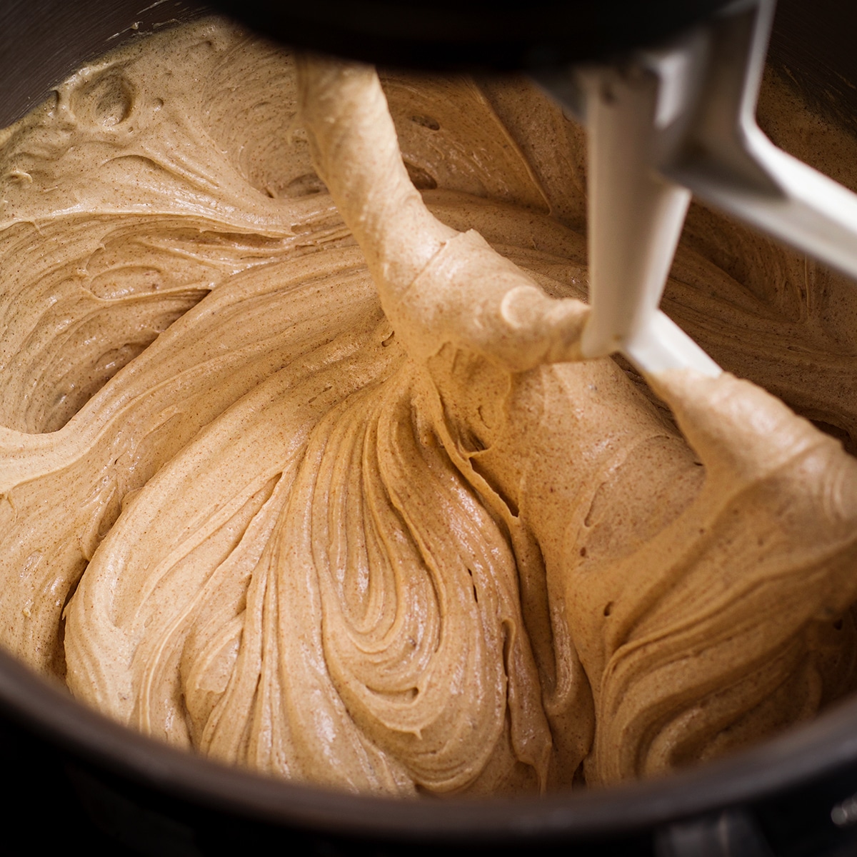 Using an electric stand mixer to beat butter, sugar, and eggs to make cookie dough.