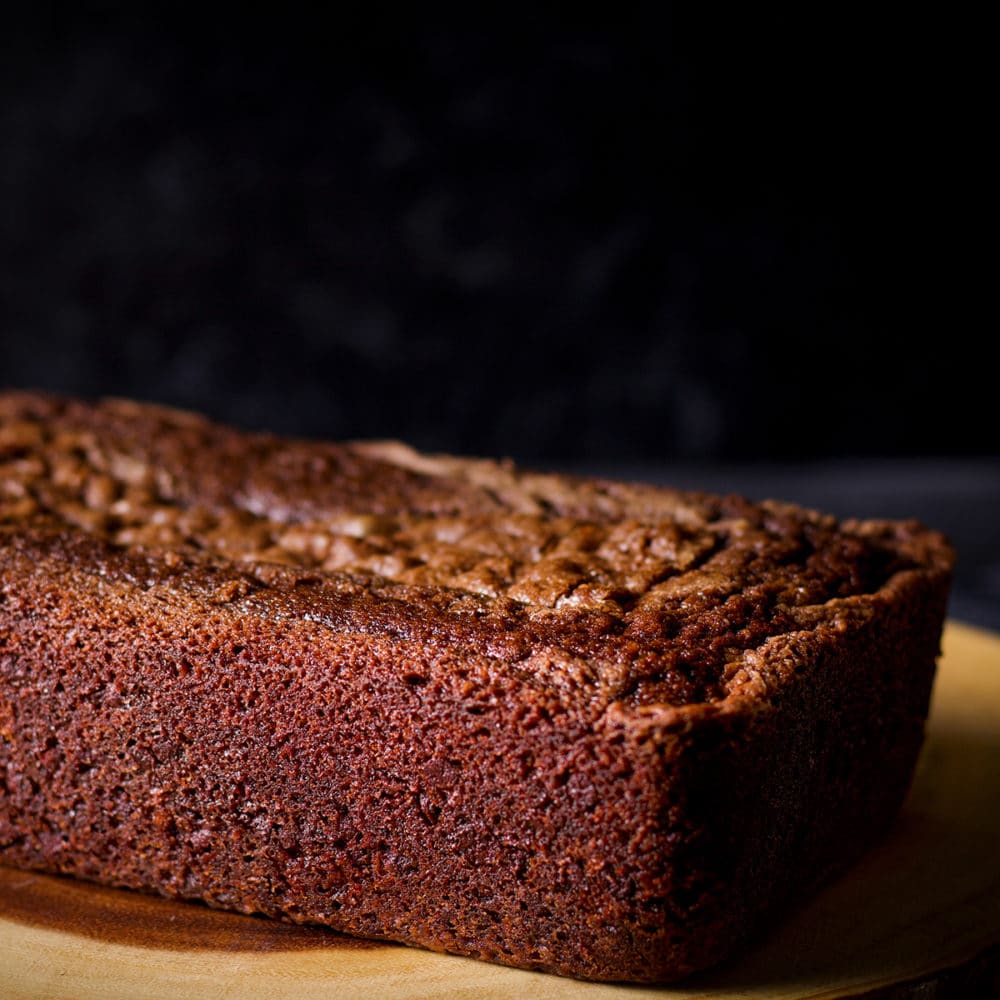 A freshly baked chocolate loaf cake on a wood serving platter.