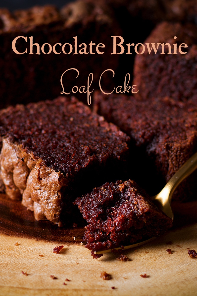 Someone using a gold fork to cut a bite of chocolate brownie loaf cake.