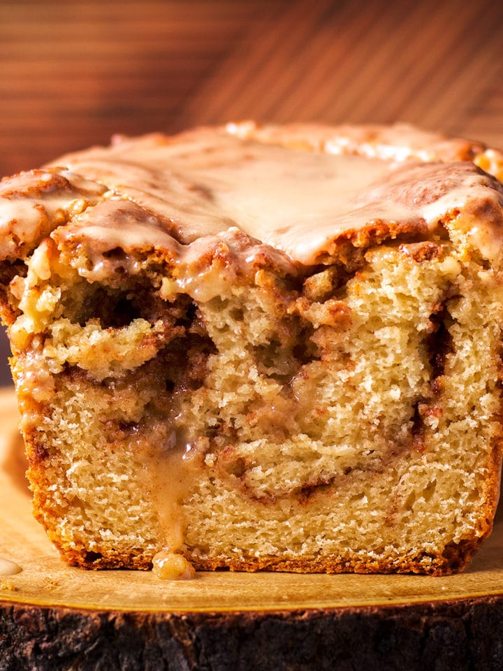 Cinnamon Swirl Loaf Cake on a wood cutting board that's been cut in half so you can see the cinnamon swirl inside the cake.