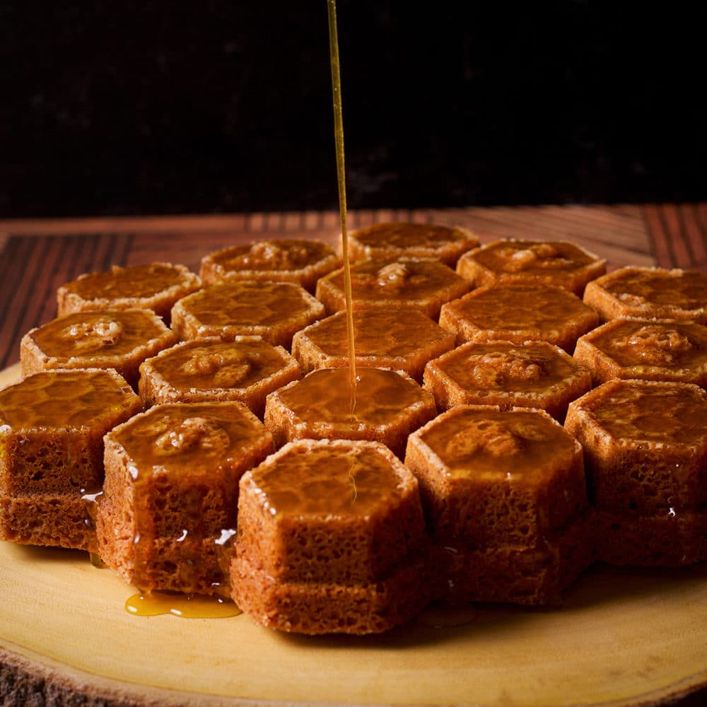 Pouring whisky sauce over the top of a freshly baked honey cake.