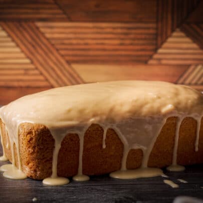 A loaf cake covered in vanilla icing, the icing dripping down the sides of the cake.