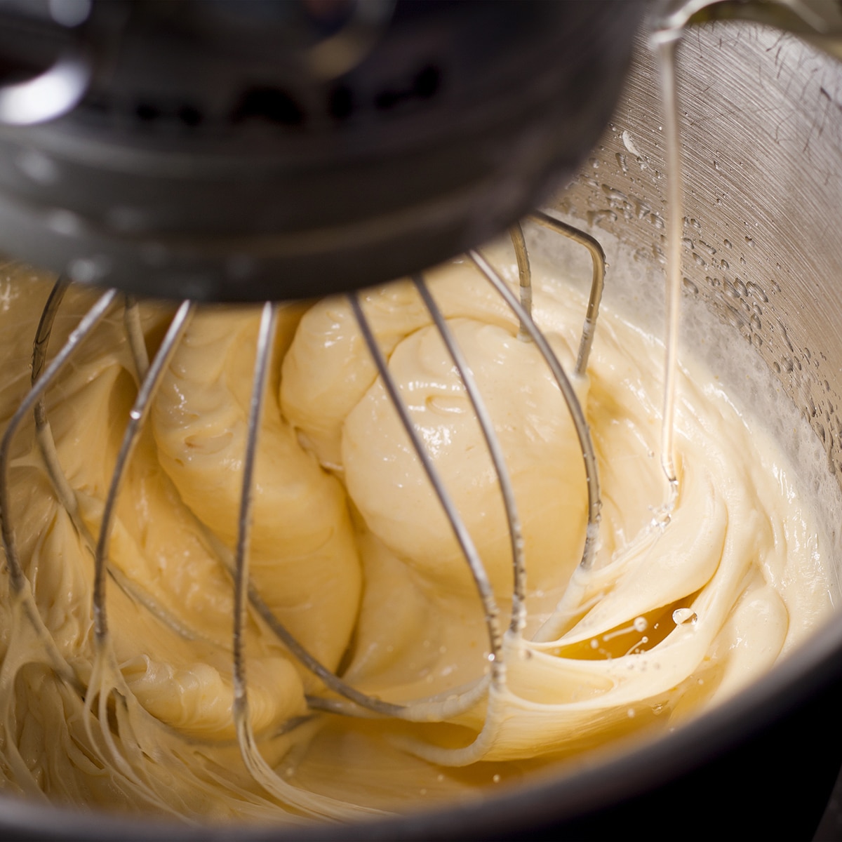 Pouring oil into the cake batter with the mixer running.