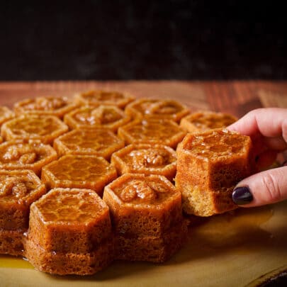 Someone taking a piece of honey cake covered in whisky sauce that has been baked in a honeycomb pan.