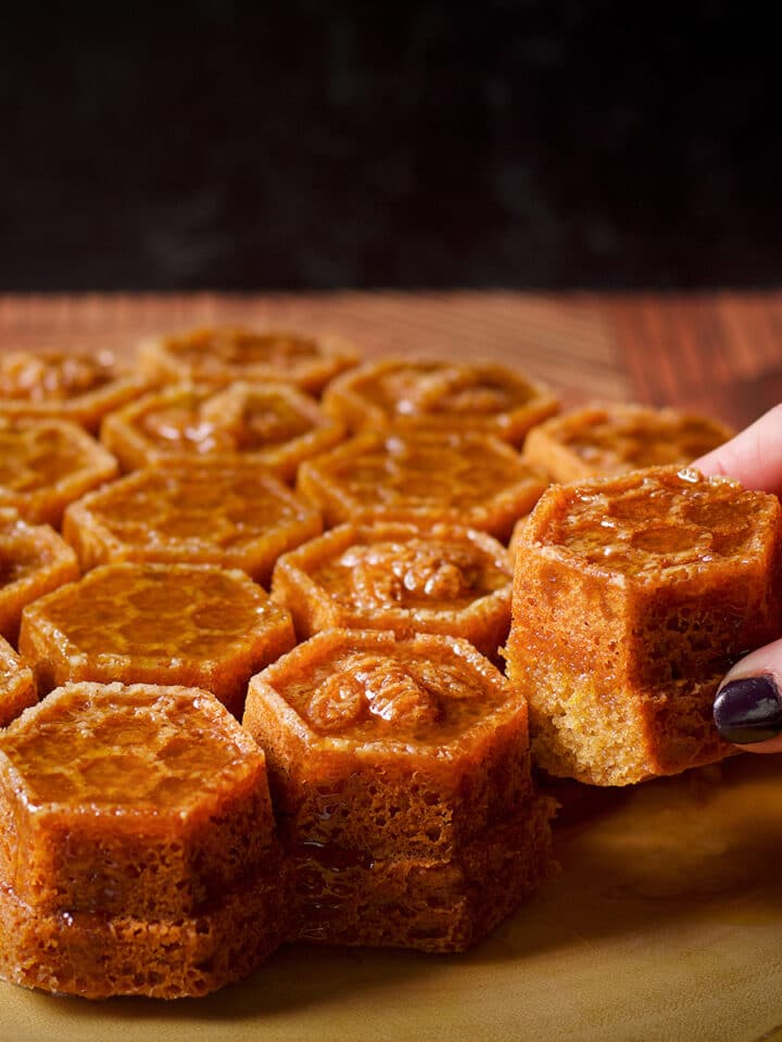 Someone taking a piece of honey cake covered in whisky sauce that has been baked in a honeycomb pan.