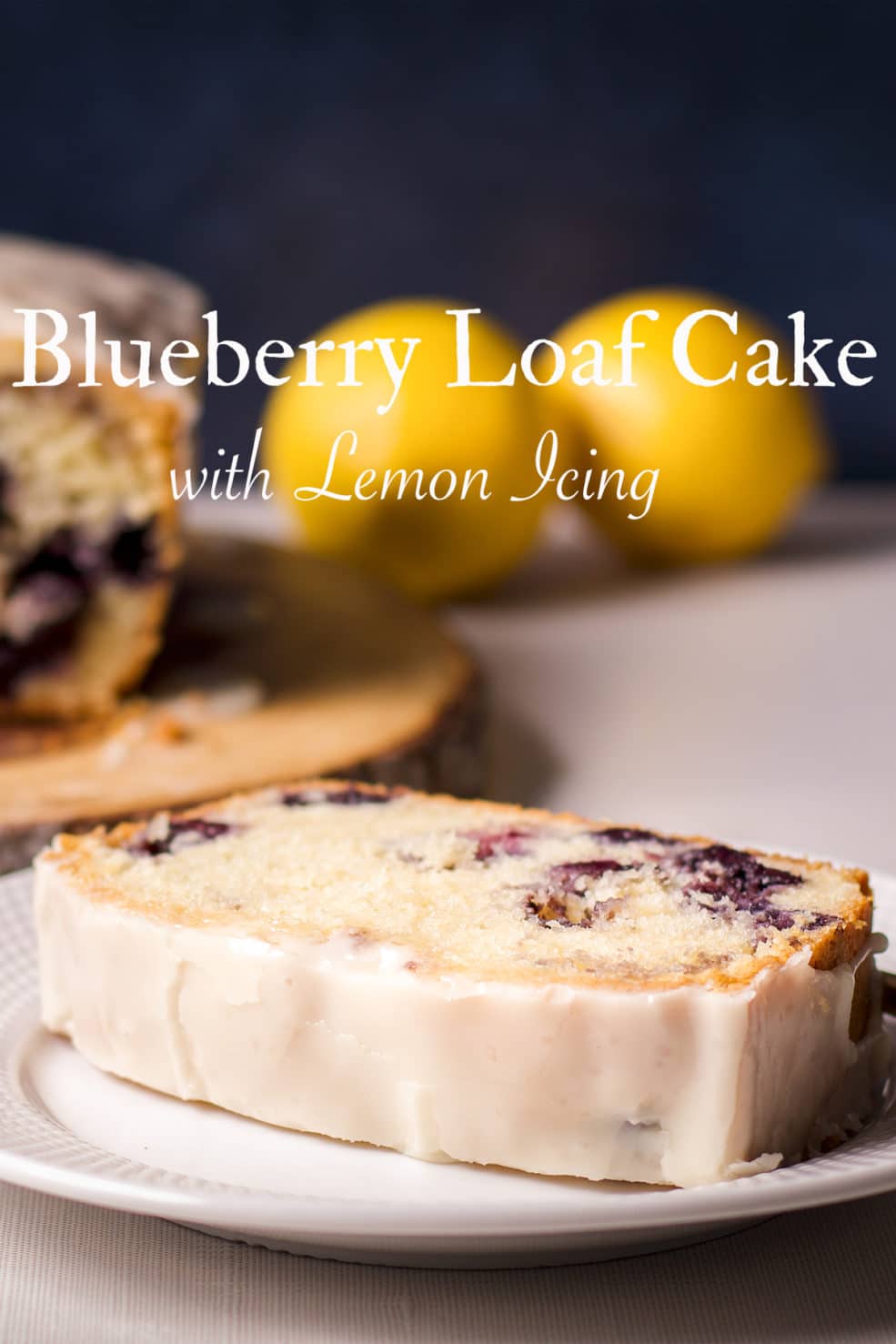 A slice of blueberry loaf cake with lemon icing on a white plate.