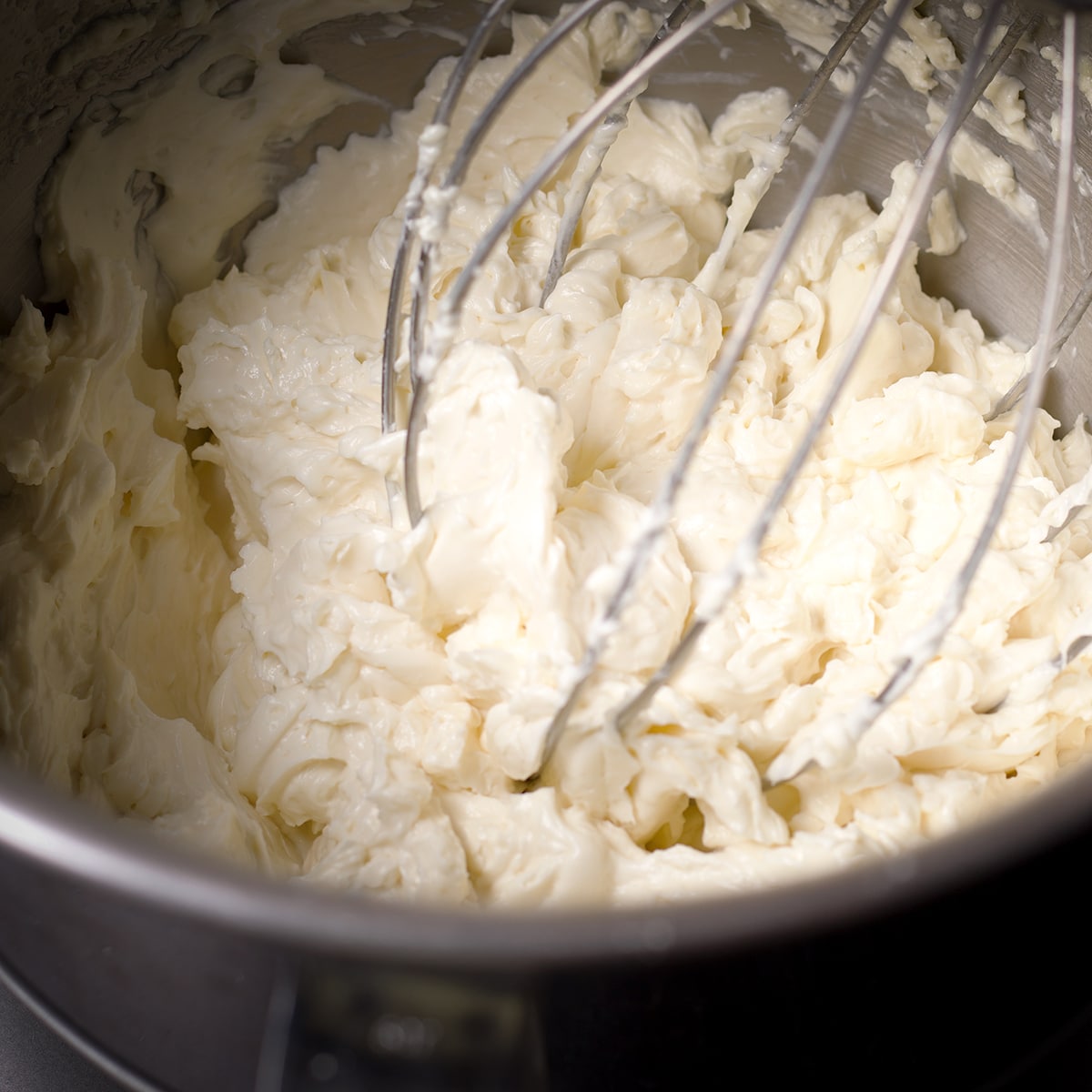 A mixer bowl filled with white chocolate ganache buttercream that's ready to use.