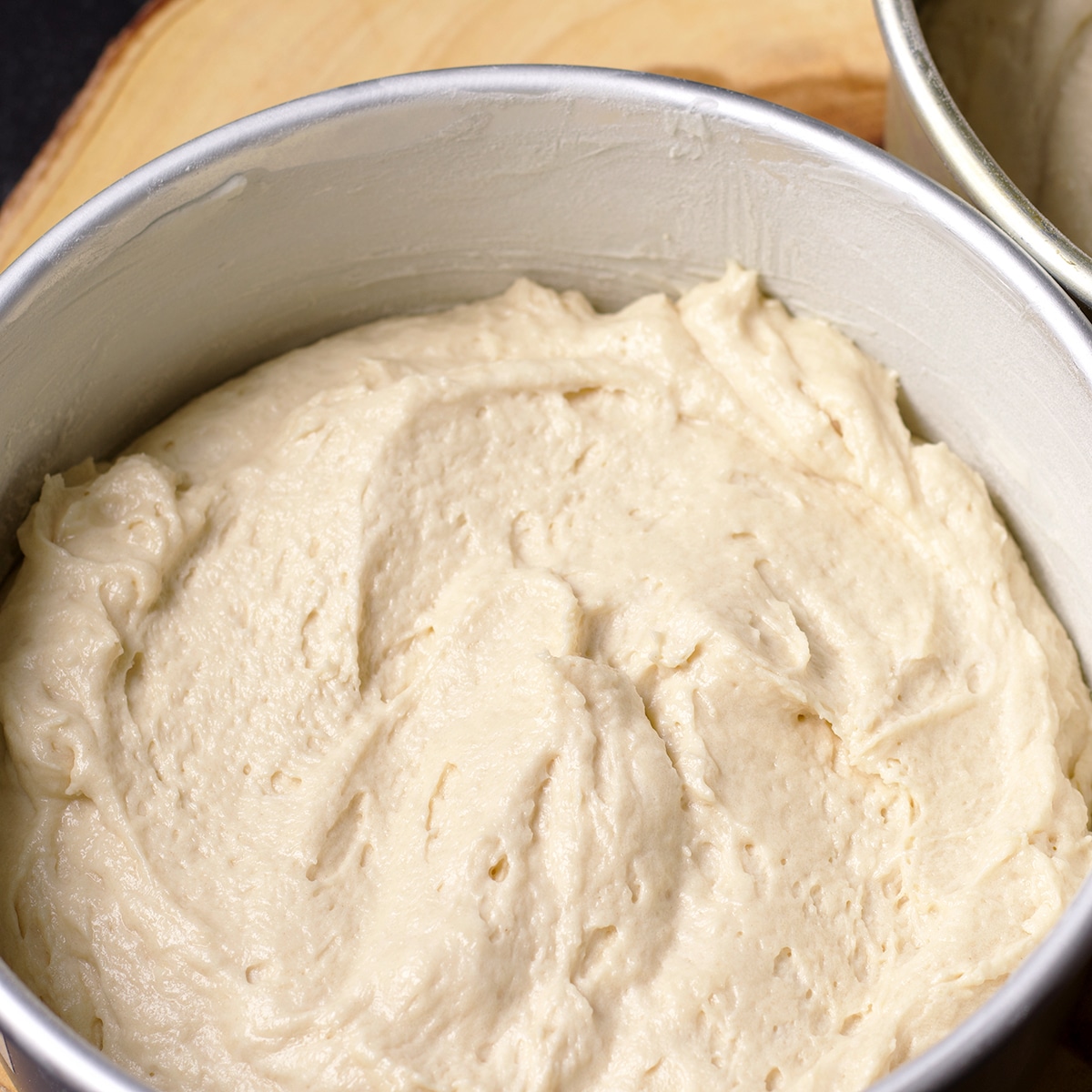Two round cake pans filled with cake batter that is ready to bake.