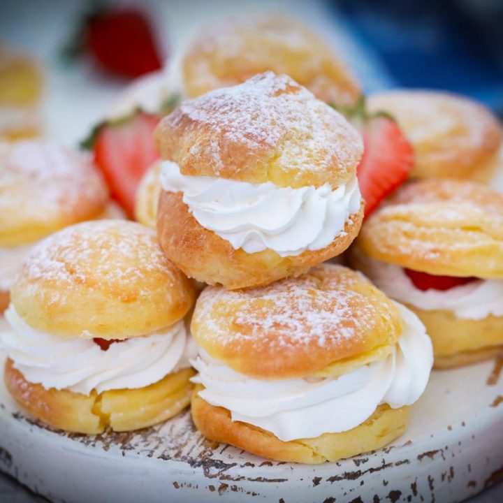 A white tray filled with whipped cream filled cream puffs.