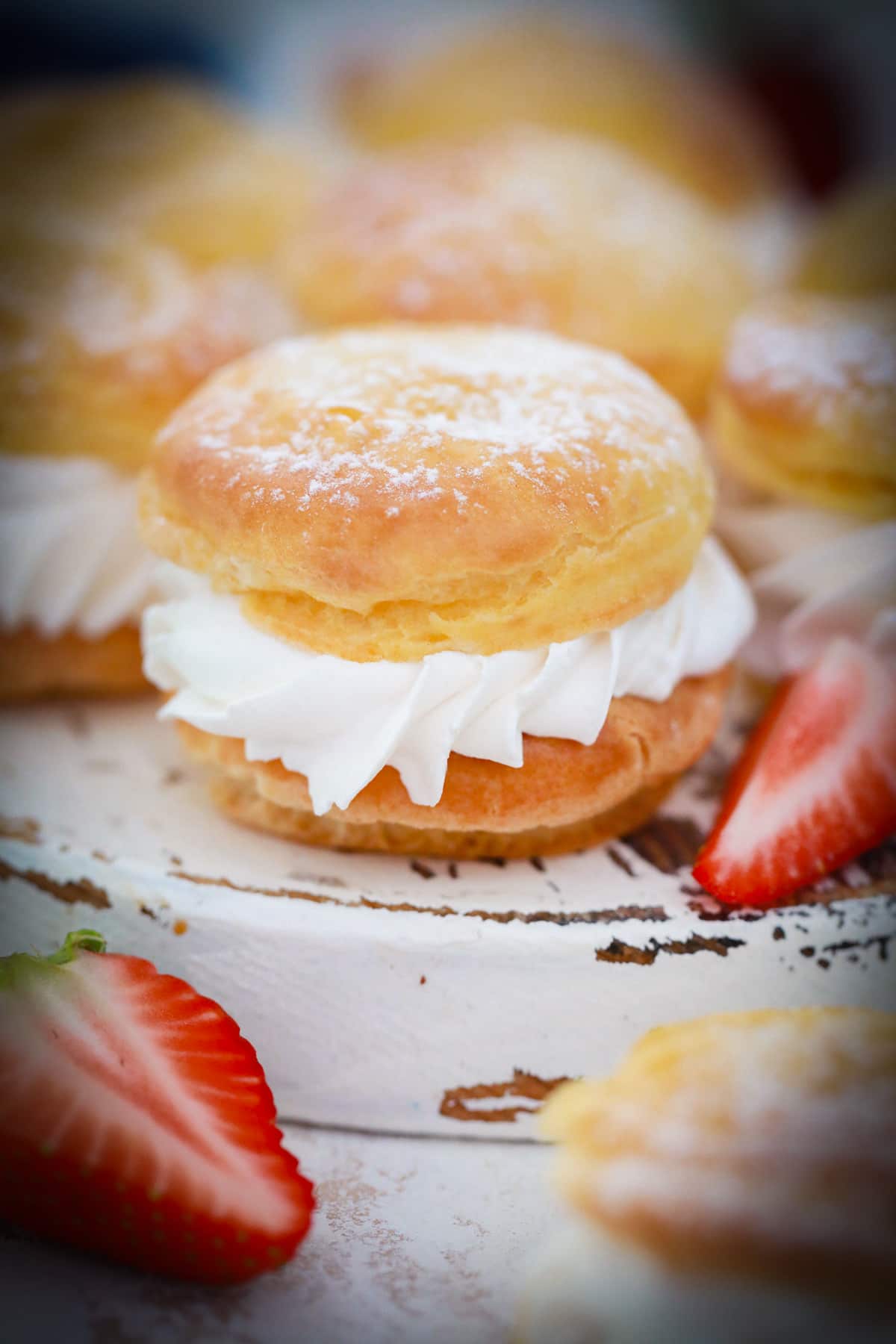 A close up photo of a whipped cream filled cream puff on a white tray.