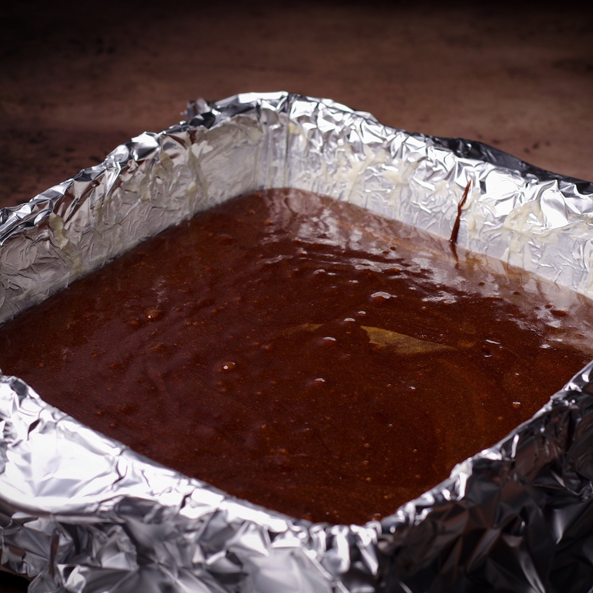 A pan of chocolate tahini brownie batter before swirling in tahini brownie batter.