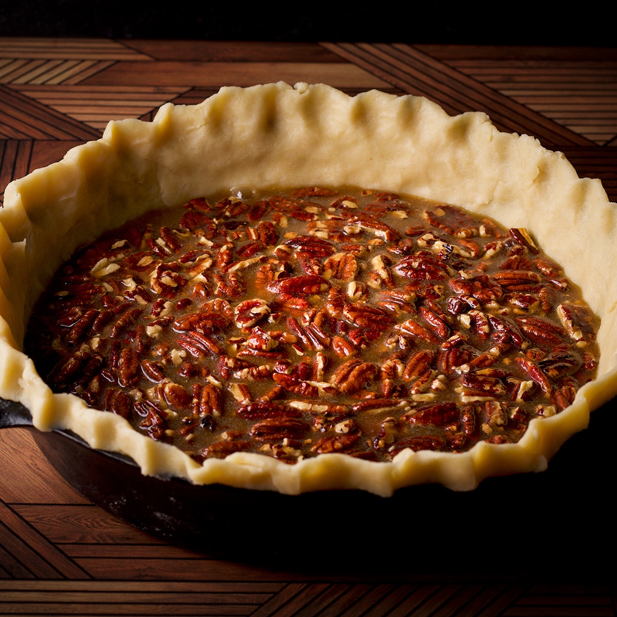 Pecan pie filling that's just been poured into a pie crust lined cast iron skillet.