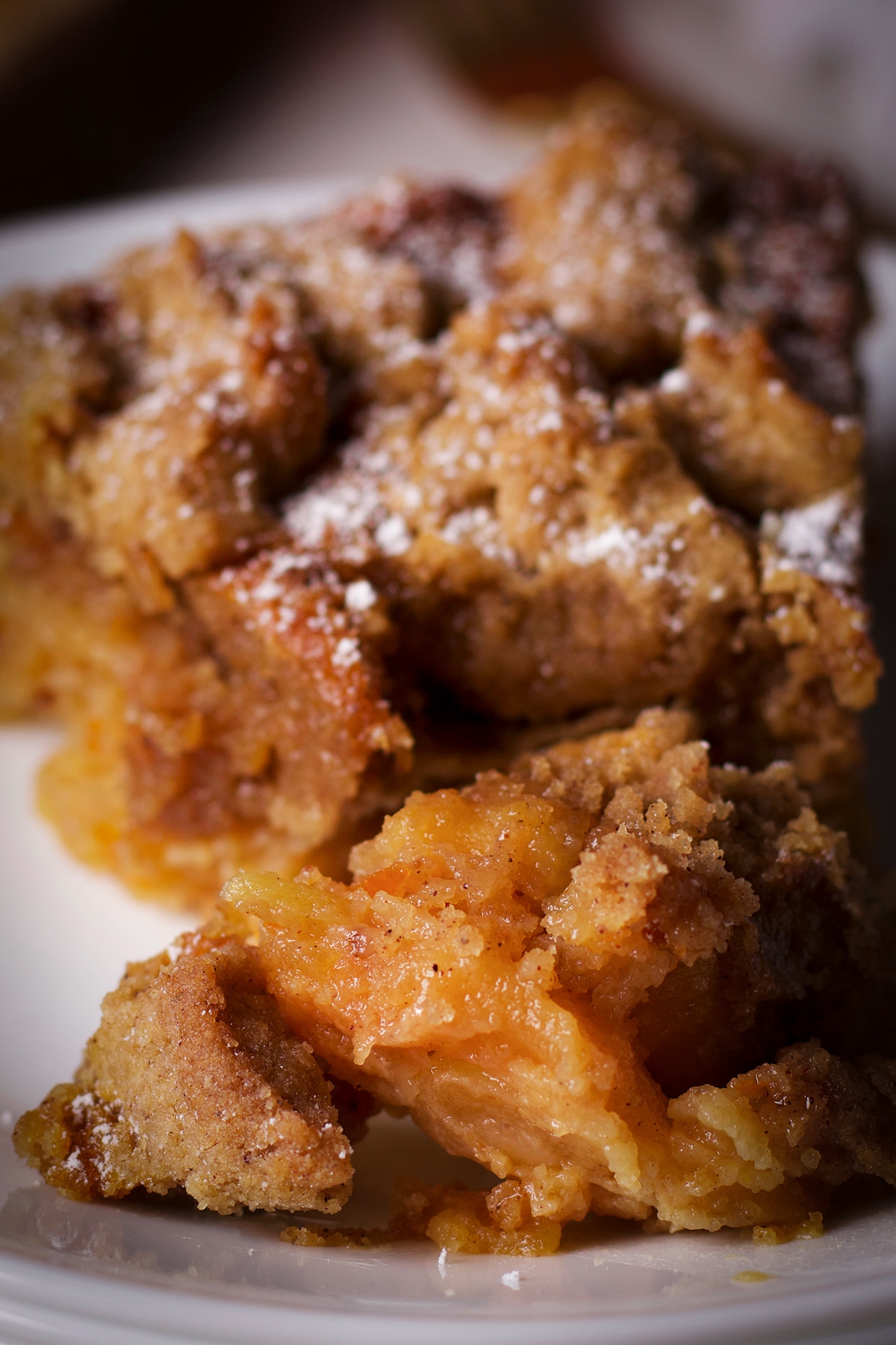 Using a fork to cut a bite of apple crumb cake from a slice.