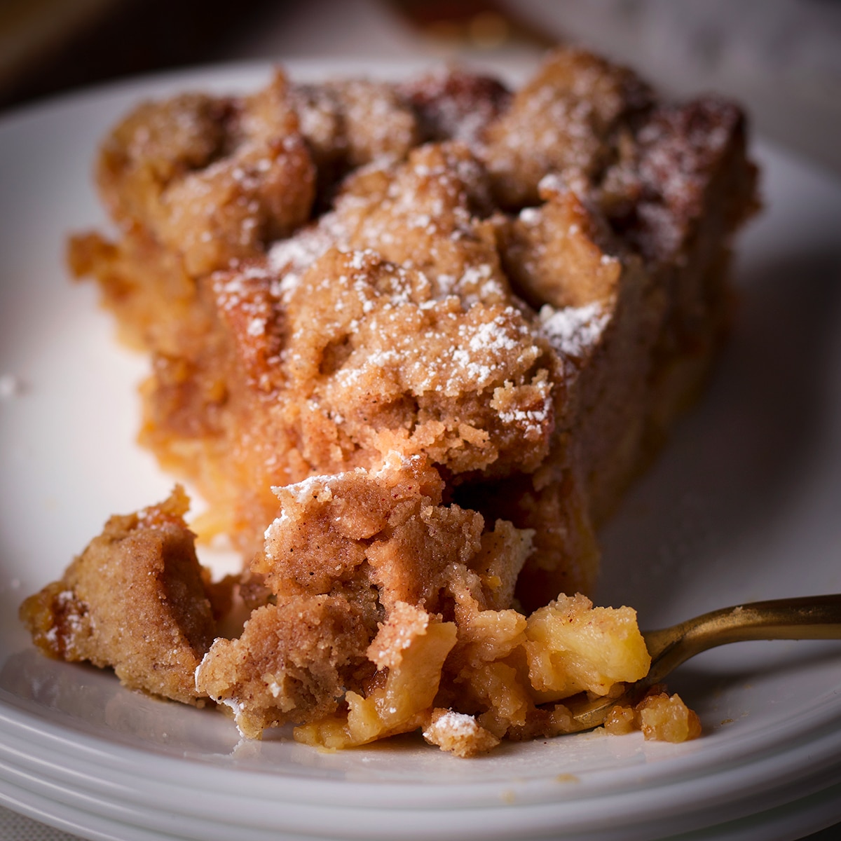 Using a fork to cut a bite of apple crumb cake from a slice.