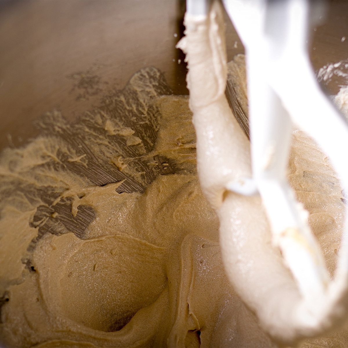 Using an electric mixer to beat butter, oil, and brown sugar.