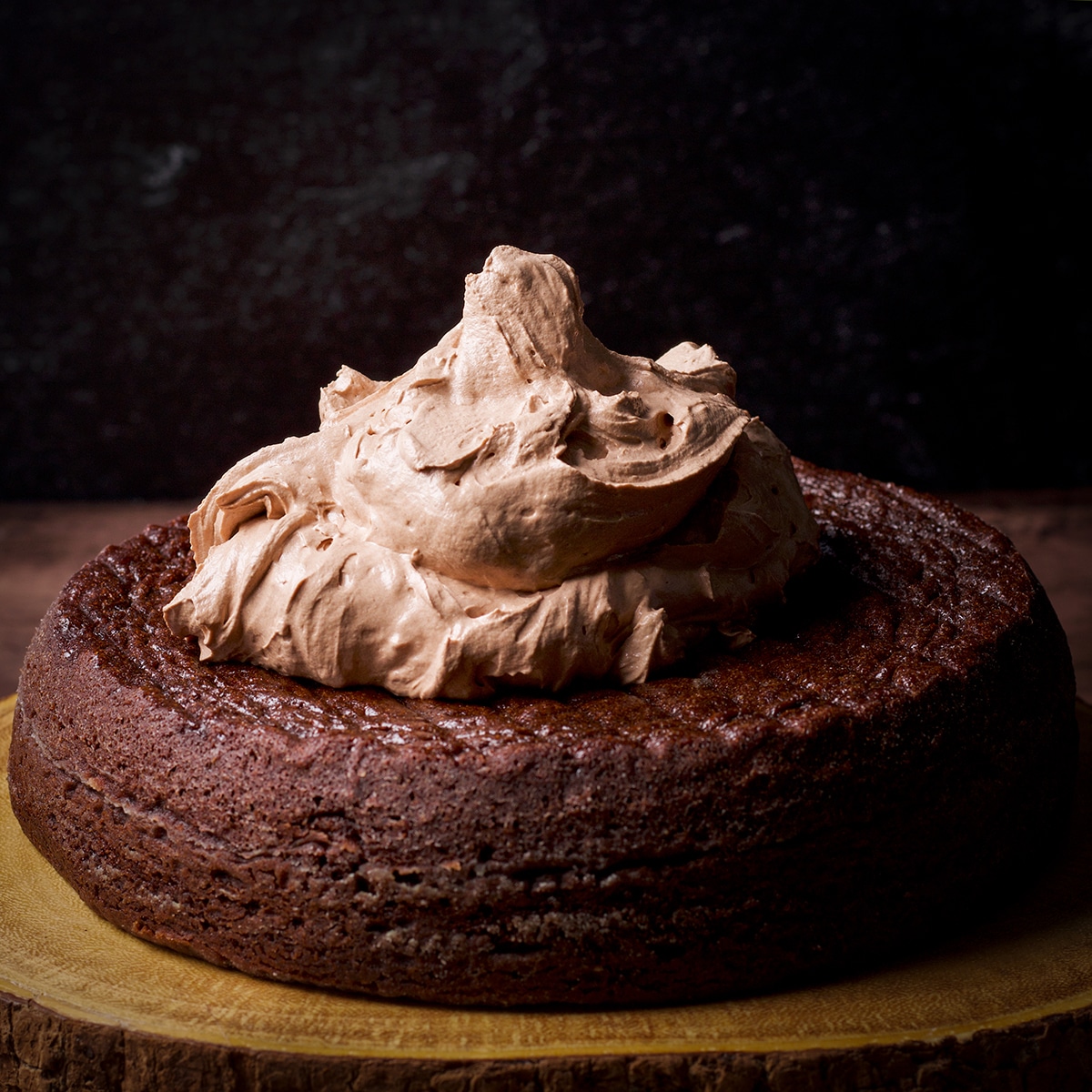 A large scoop of milk chocolate buttercream in the center of a round dark chocolate cake layer.
