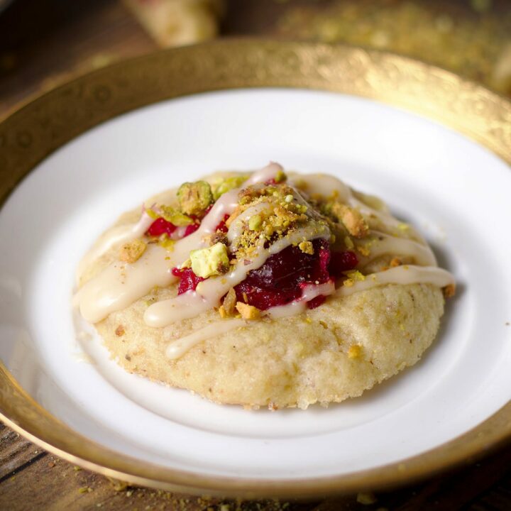 A cranberry pistachio cookie on a small gold-trimmed dessert plate.