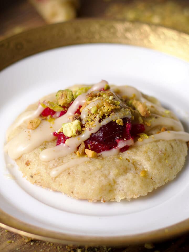 A cranberry pistachio cookie on a small gold-trimmed dessert plate.