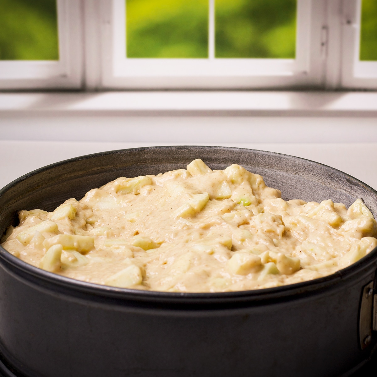 A springform pan containing Irish Apple Cake batter, ready to bake.