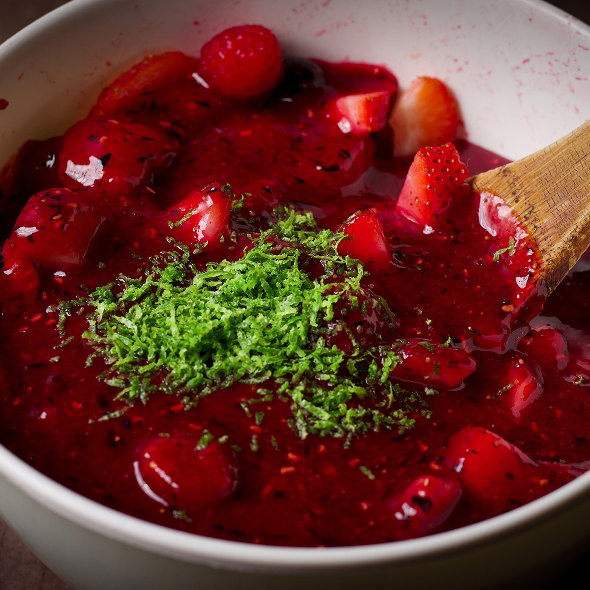 Lime zest sprinkled over a bowl of easy berry sauce.