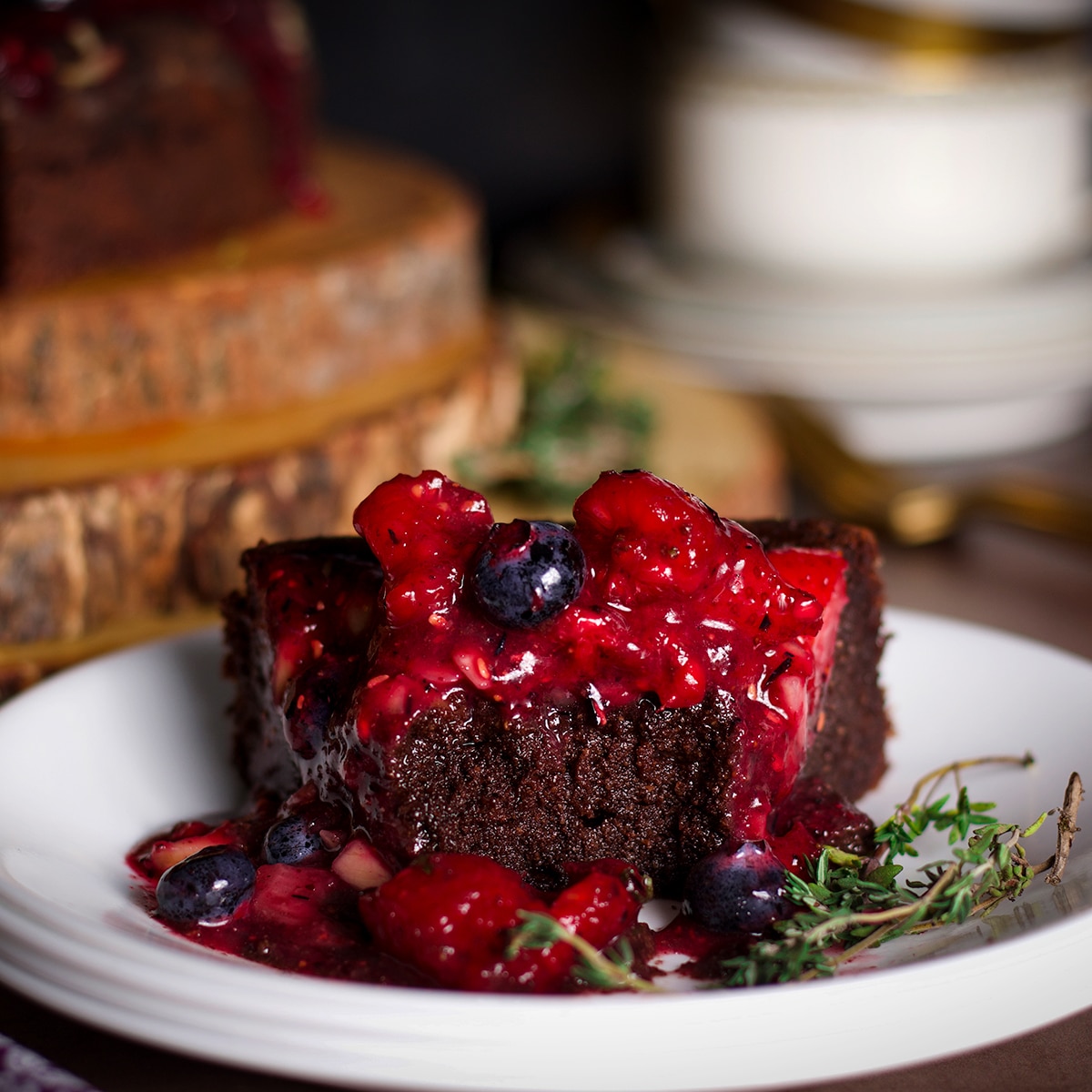 A slice of chocolate ricotta cake covered in fresh berry sauce with a bite taken out of it.