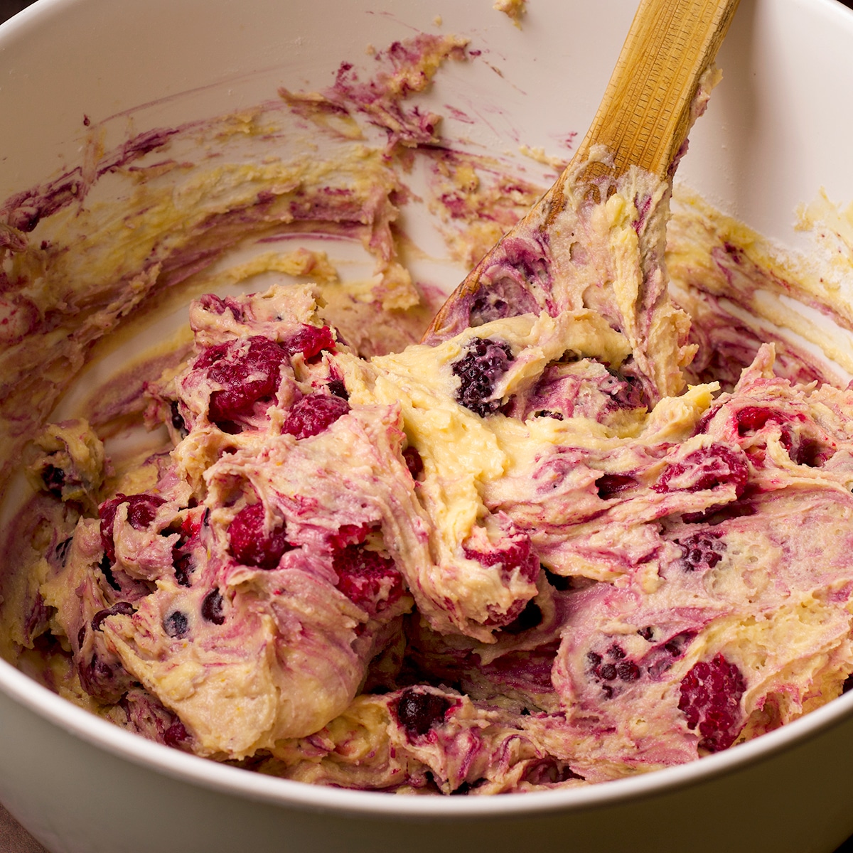Using a wooden spoon to mix berries into muffin batter.
