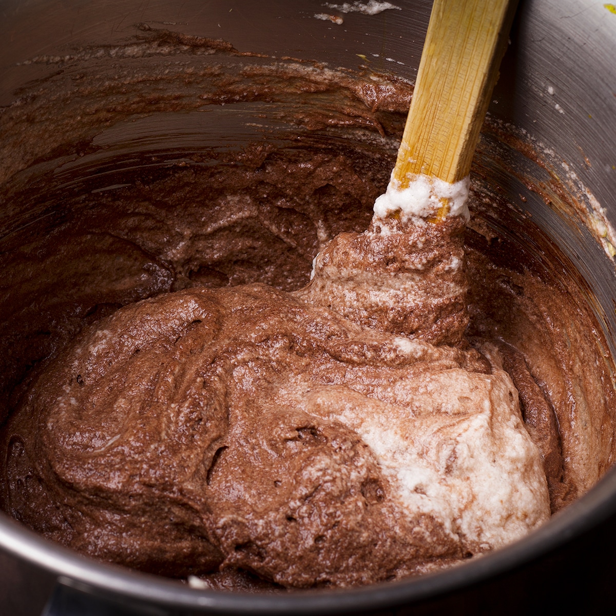 Using a wood spoon to fold beaten egg whites into chocolate ricotta cake batter.