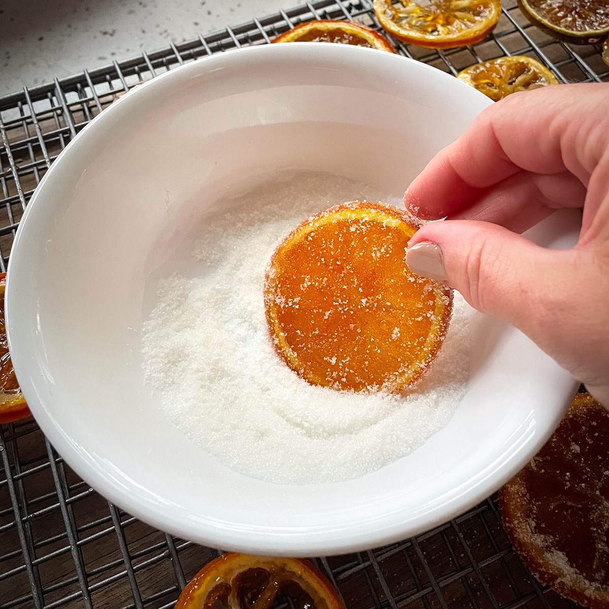 Dipping a candied orange slice in granulated sugar.