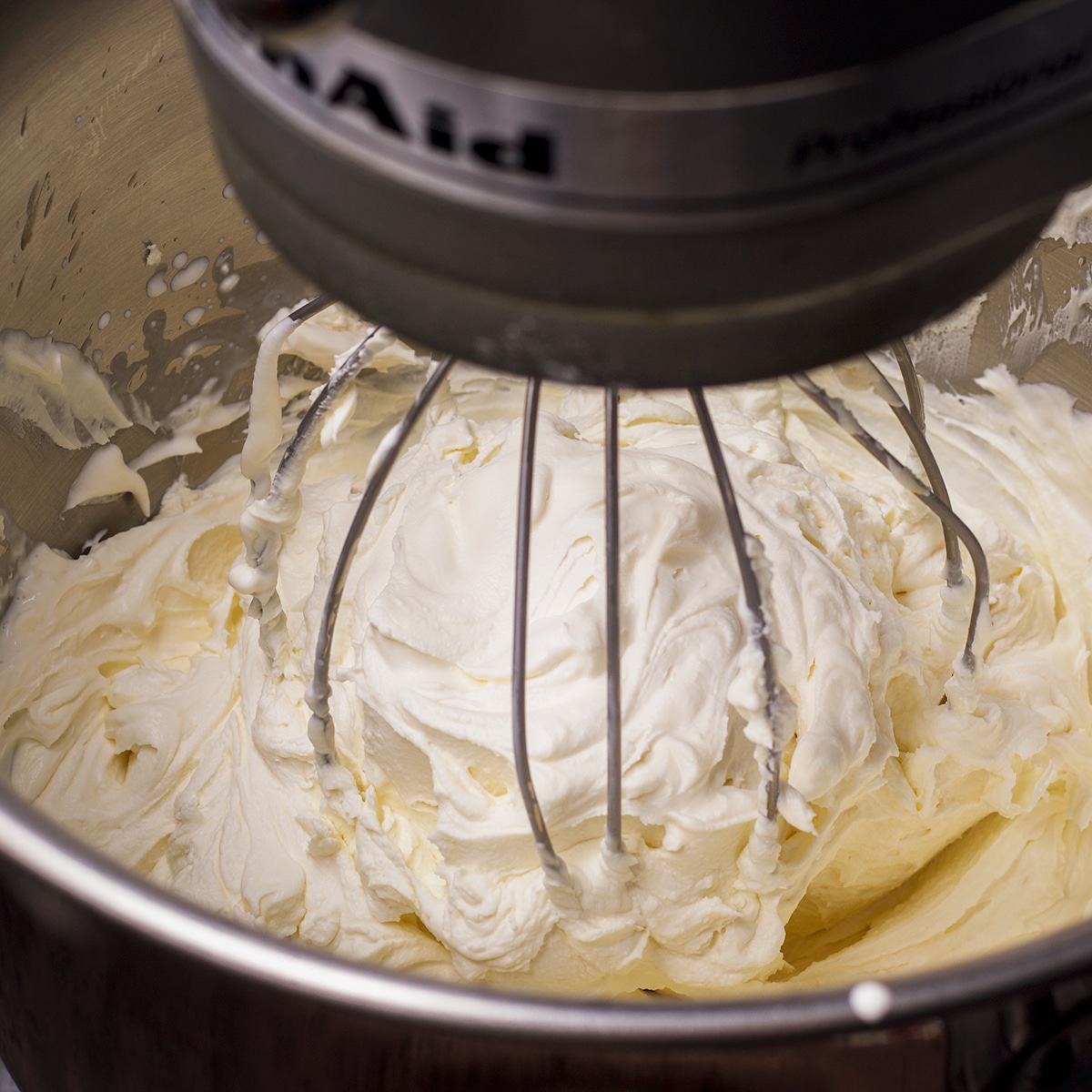Using an electric mixer to beat mascarpone frosting.