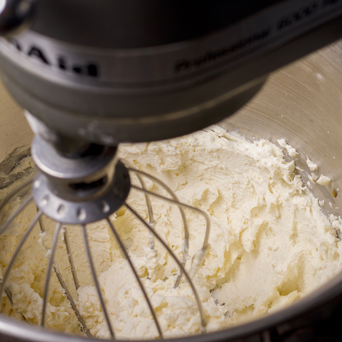 Using an electric mixer to beat mascarpone cheese and sugar.