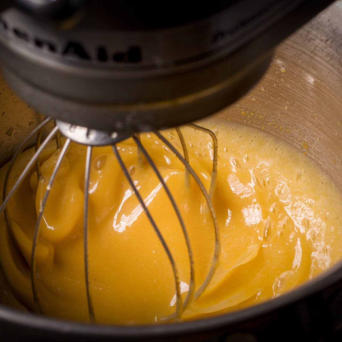 Using an electric mixer to beat oil, eggs, buttermilk, orange juice, vanilla, and sugar.