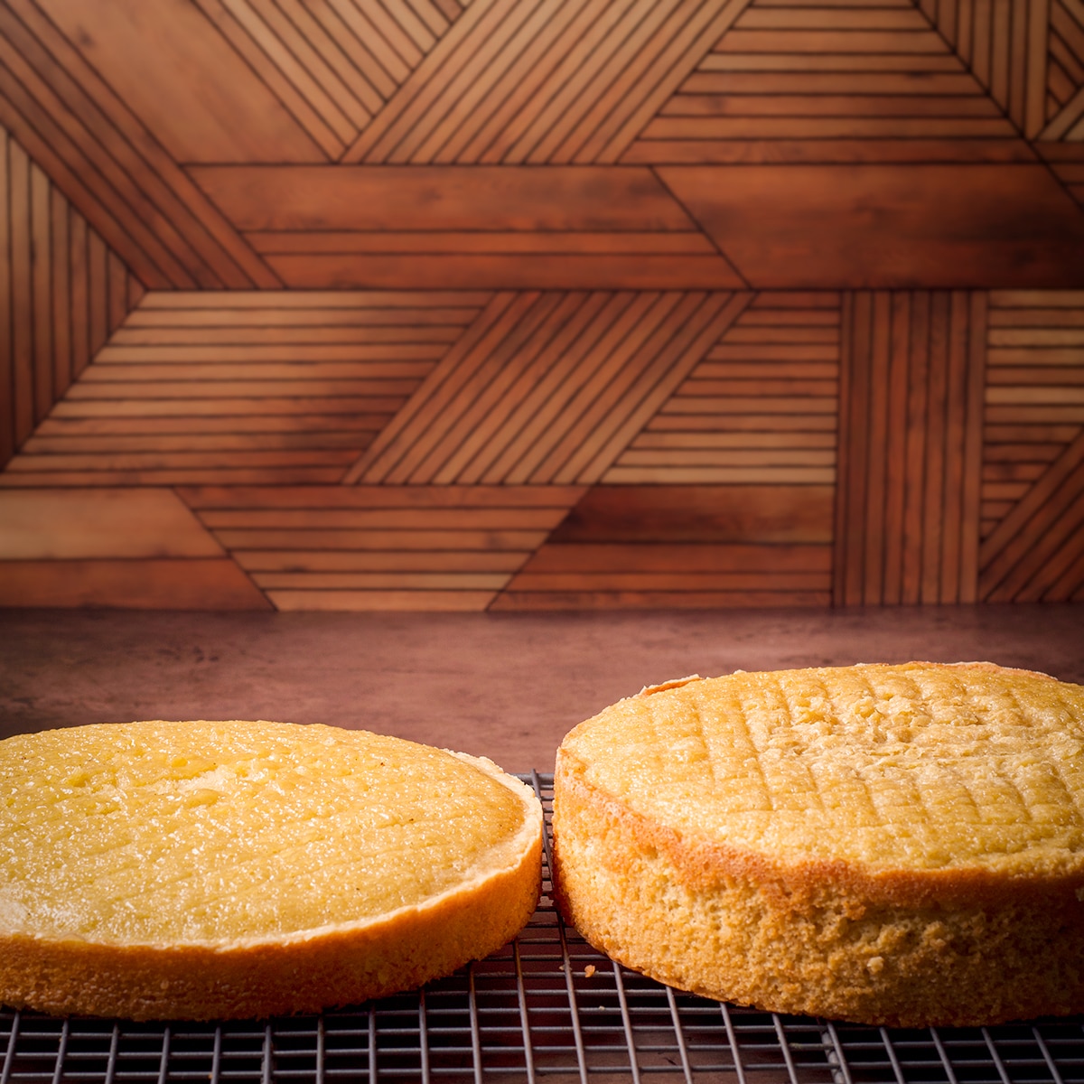 Two orange olive oil cake layers resting on wire racks.