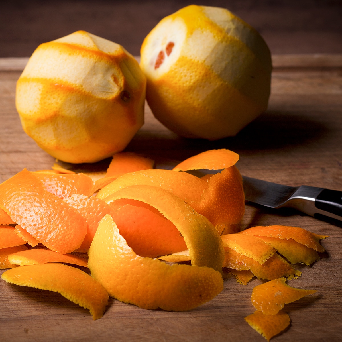 Cutting the peel from two oranges.