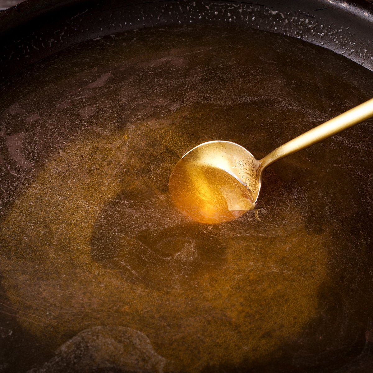 Stirring sugar and water in a skillet while it cooks on the stovetop.