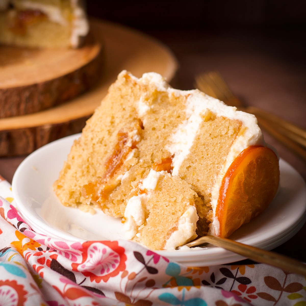 A slice of 3-layer orange olive oil cake filled with orange marmalade and covered in mascarpone frosting.