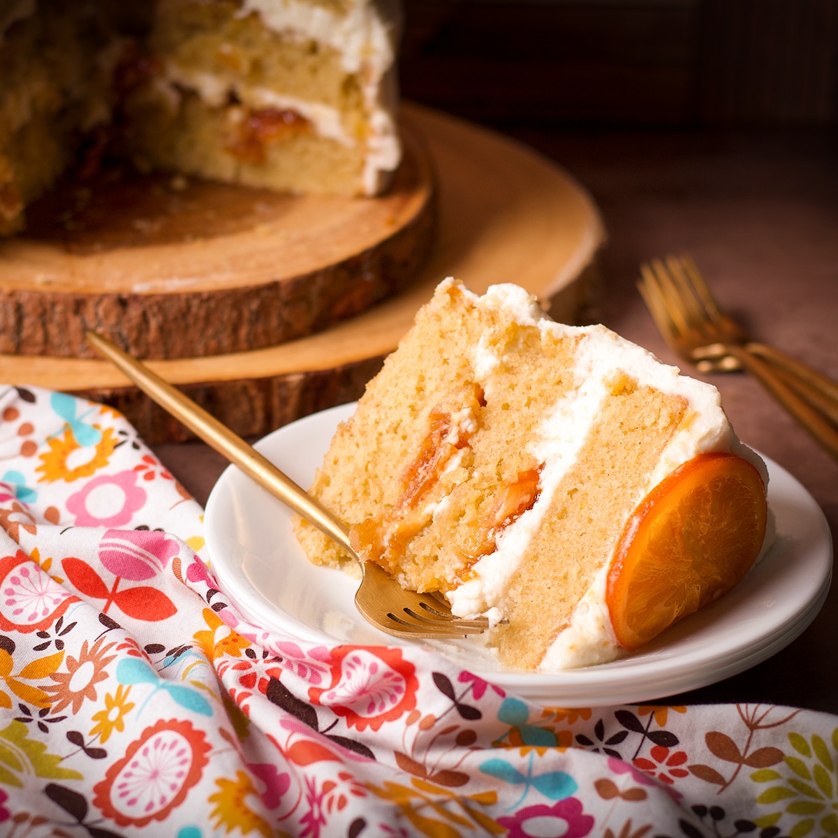A slice of 3-layer orange olive oil cake filled with orange marmalade and covered in mascarpone frosting.