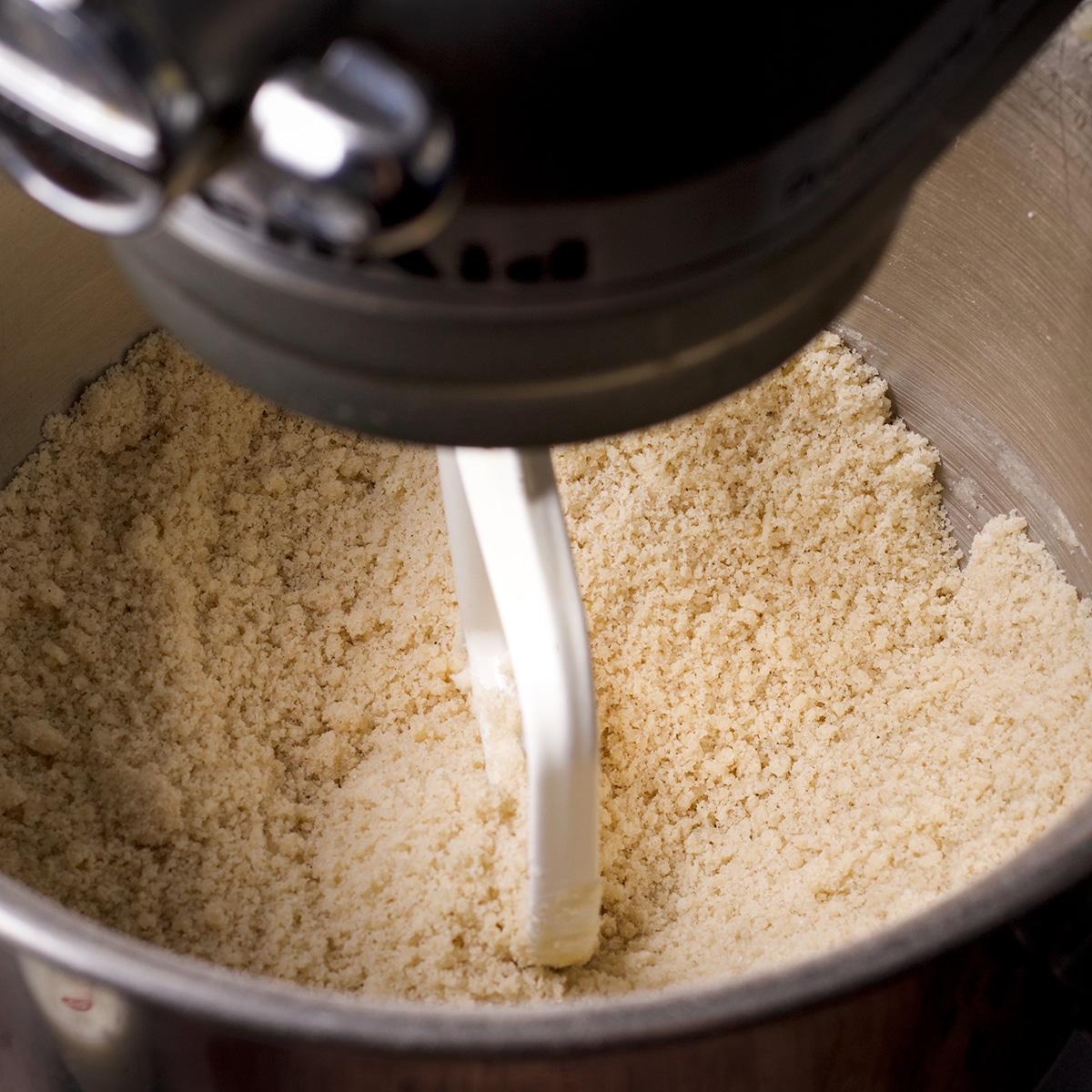 Mixing butter into flour and sugar until the texture resembles coarse crumbs.