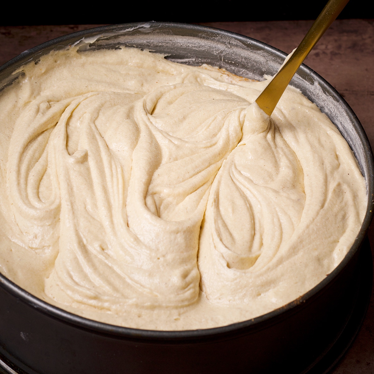 Using a butter knife to swirl cinnamon sugar into cake batter.