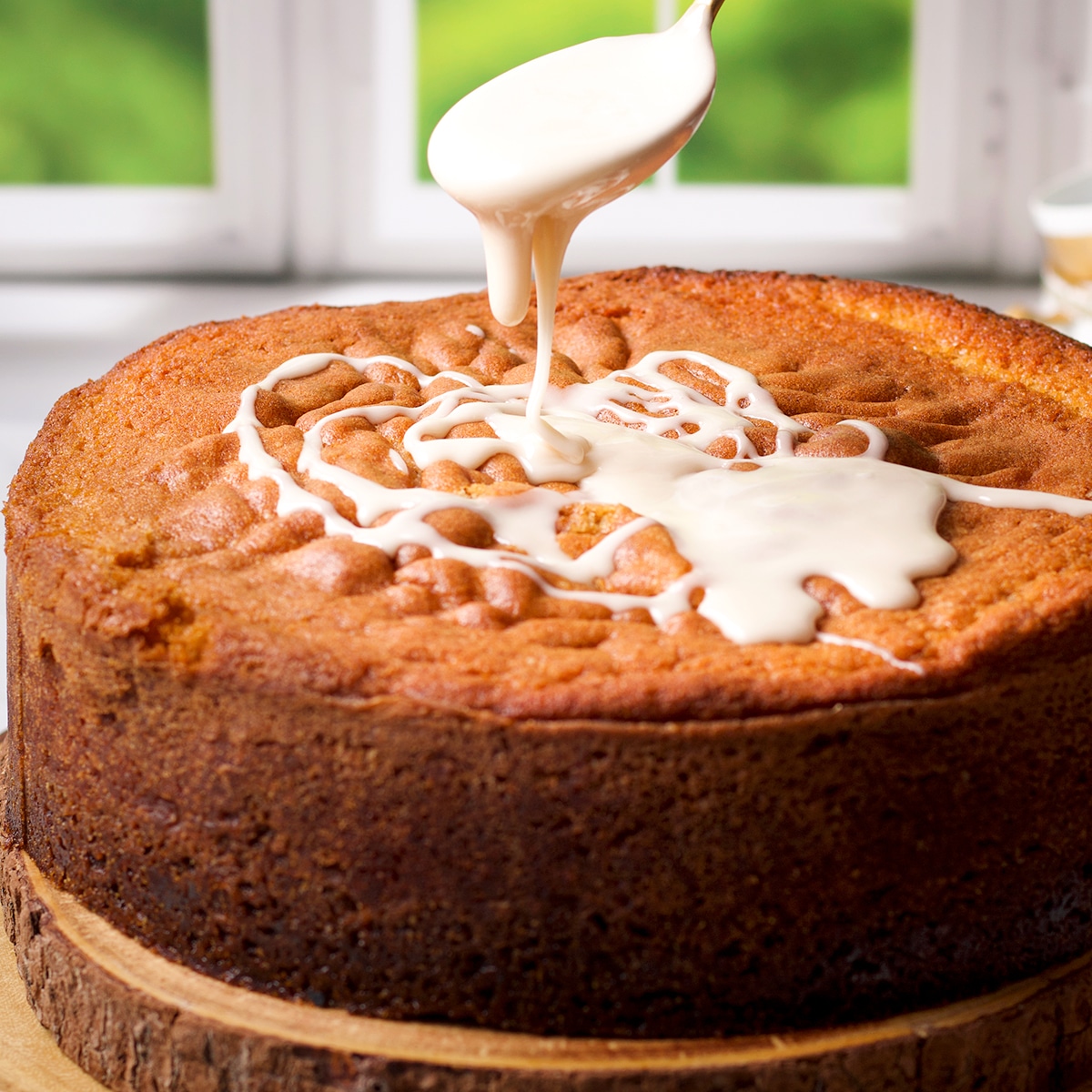 Using a spoon to drizzle buttermilk coffee cake with simple vanilla glaze.