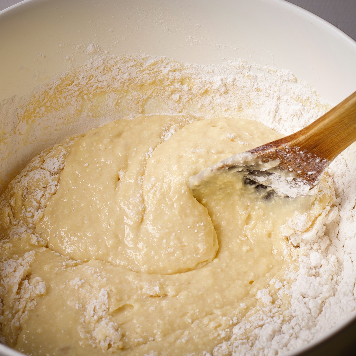 Using a wooden spoon to stir raspberry muffin batter.