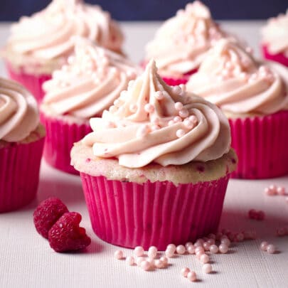 Several raspberry cupcakes topped with a swirl of raspberry cream cheese frosting.