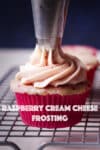 Using a pastry bag and cupcake tip to pipe a swirl of raspberry cream cheese frosting on a raspberry cupcake.