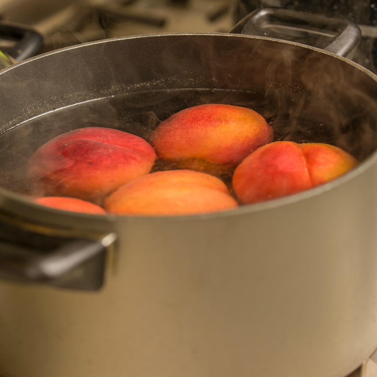 Whole peaches in a pot of boiling water.
