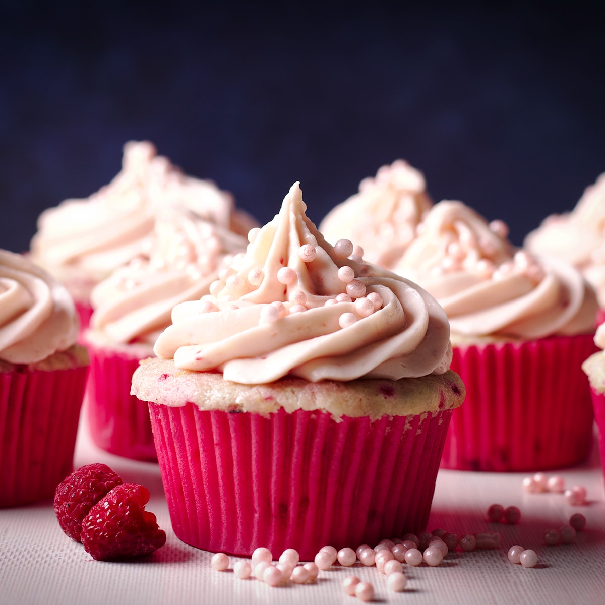 Several raspberry cupcakes topped with a swirl of raspberry cream cheese buttercream.
