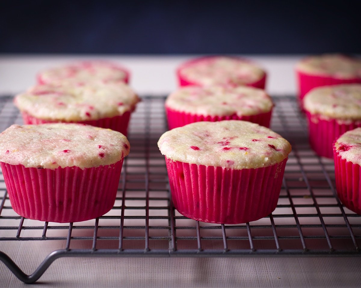 Freshly baked raspberry cupcakes cooling on a wire baking rack.