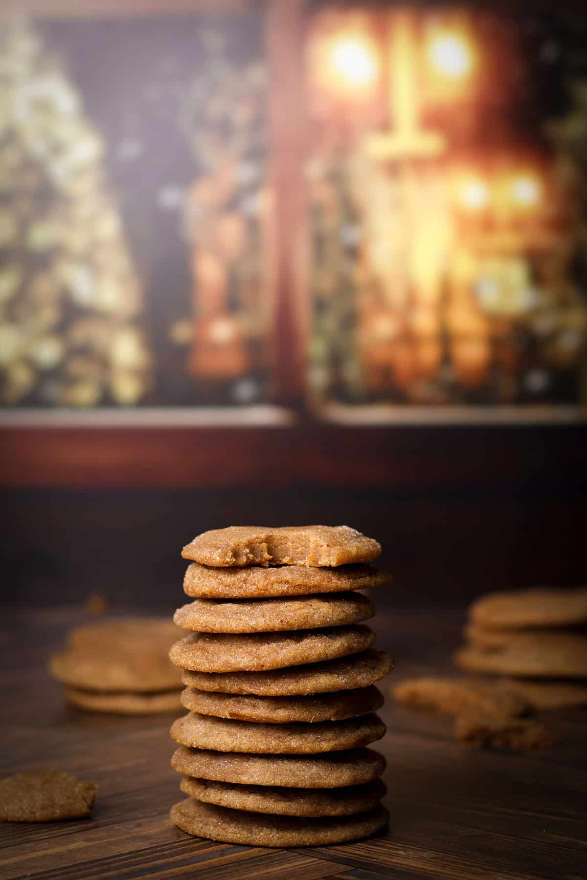 A tall stack of vanilla bean brown sugar cookies with a bite taken out of the cookie on the top of the stack.